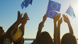 People with raised hands waving flags of the European Union